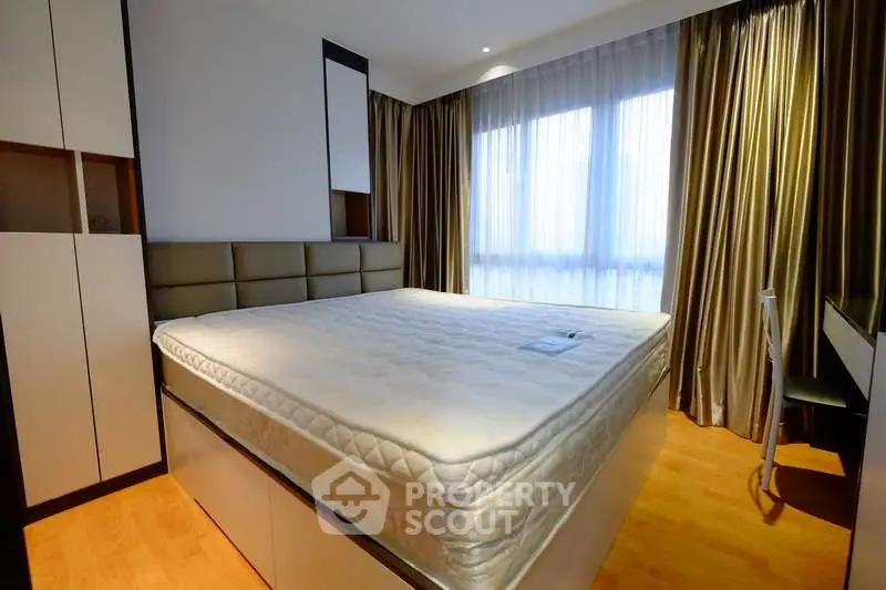 Spacious bedroom with large windows and modern furnishings in a stylish apartment.