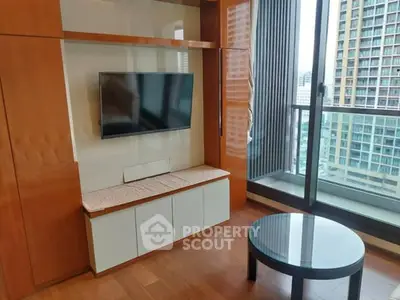 Modern living room with TV and balcony view in high-rise apartment