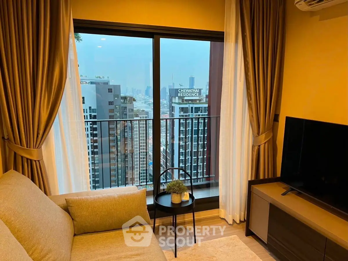 Modern living room with city view from balcony, cozy sofa, and large TV setup.