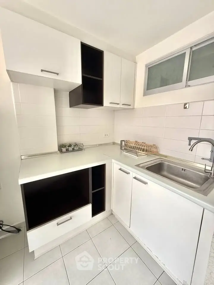 Modern kitchen with sleek white cabinetry and stainless steel sink, perfect for urban living.