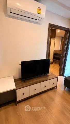 Modern living room with sleek TV stand and air conditioning, showcasing cozy and stylish interior design.