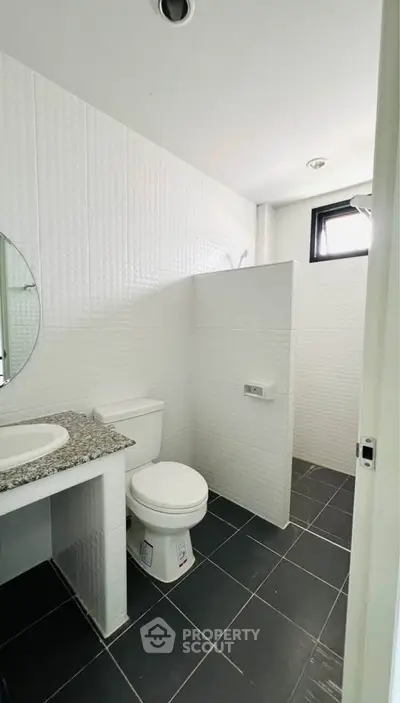 Modern bathroom with sleek design, featuring a granite countertop and stylish tile flooring.