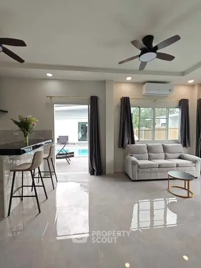 Spacious living room with modern decor and pool view, perfect for relaxation and entertaining.