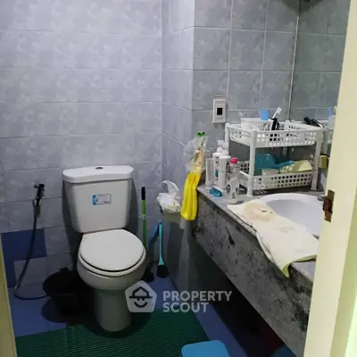 Compact bathroom with tiled walls and essential amenities in a cozy home setting.