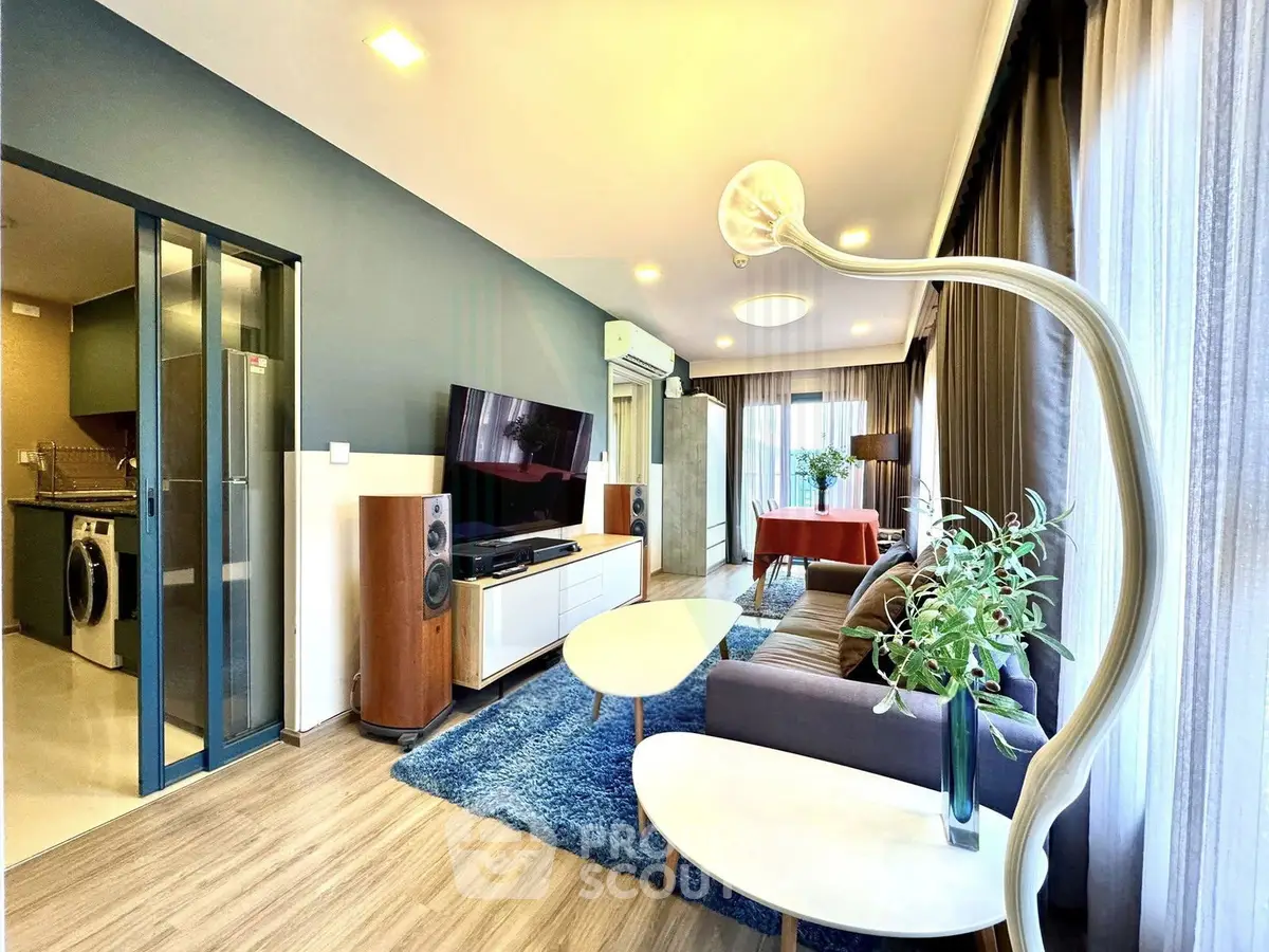 Modern living room with stylish decor, large windows, and open layout connecting to dining area.