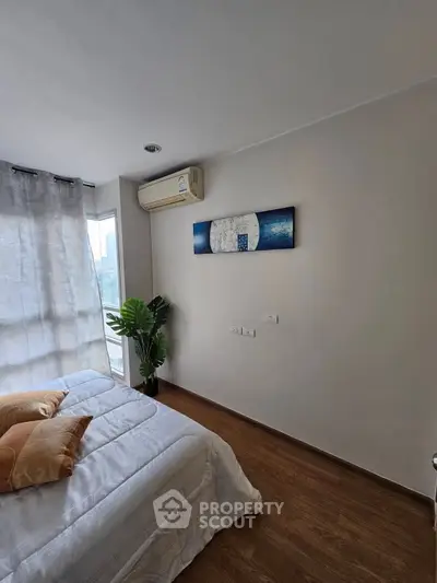 Modern bedroom with wooden flooring, air conditioning, and stylish decor in a bright apartment.