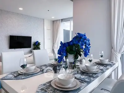 Elegant dining area with modern decor and vibrant blue floral centerpiece in a stylish apartment.