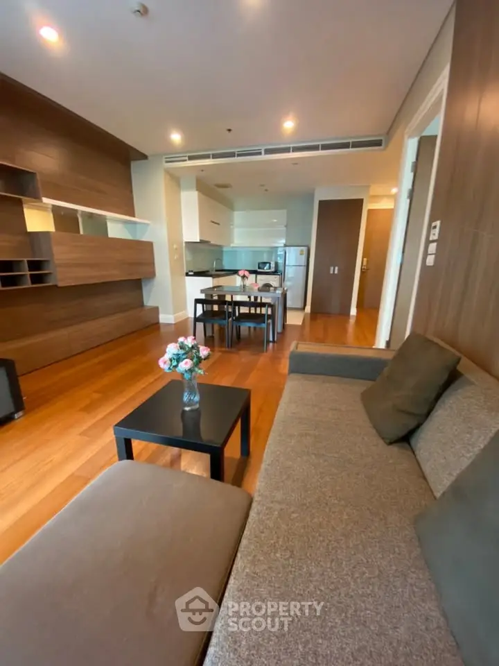 Modern living room with open kitchen, stylish decor, and wooden flooring in a contemporary apartment.