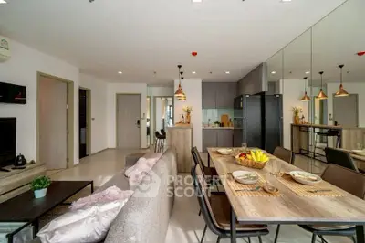 Modern open-plan living and dining area with stylish decor and mirrored wall.