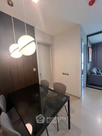 Modern dining area with sleek black table and stylish lighting in a contemporary apartment.