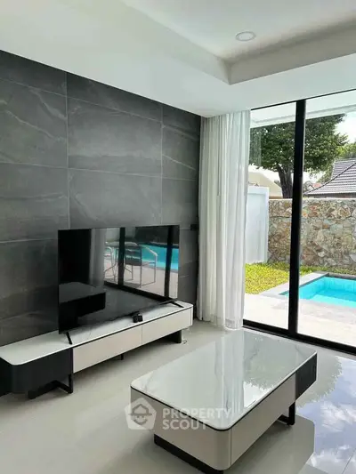 Modern living room with sleek design and pool view, featuring large TV and stylish furniture.