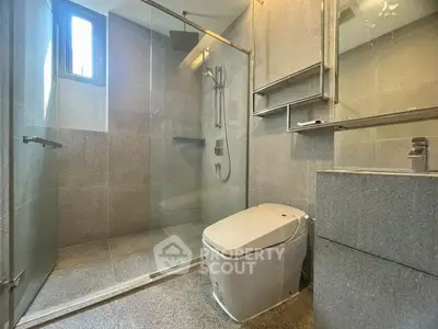 Modern bathroom with sleek design, featuring a glass-enclosed shower and contemporary fixtures.