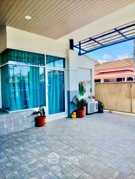Charming residential entrance with covered patio and vibrant blue curtains, perfect for relaxation.