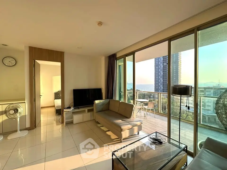 Spacious living room with modern furniture and large balcony offering stunning city views.