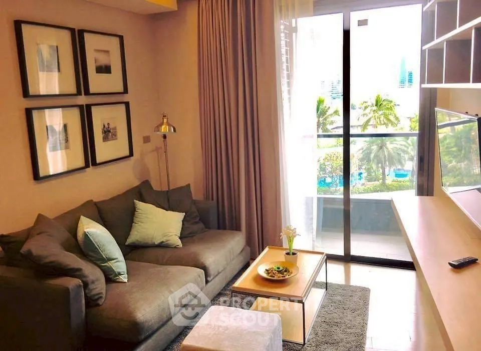 Cozy living room with modern decor and balcony view of lush greenery.