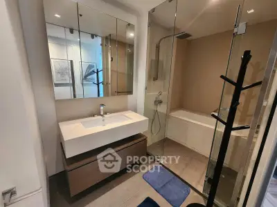 Modern bathroom with glass shower and bathtub in stylish apartment