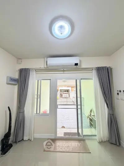 Bright living room with large window and air conditioning, offering a view of the outdoor area.