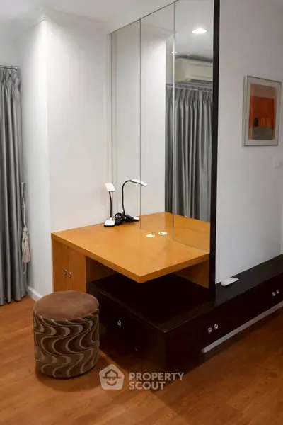 Modern bedroom with stylish vanity and mirror, featuring elegant wood flooring and contemporary decor.