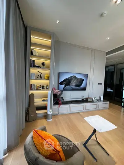 Modern living room with stylish decor and built-in shelving, featuring a cozy seating area and large TV.