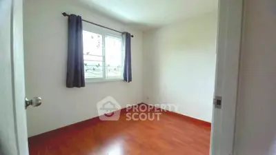 Bright empty bedroom with wooden flooring and window view.