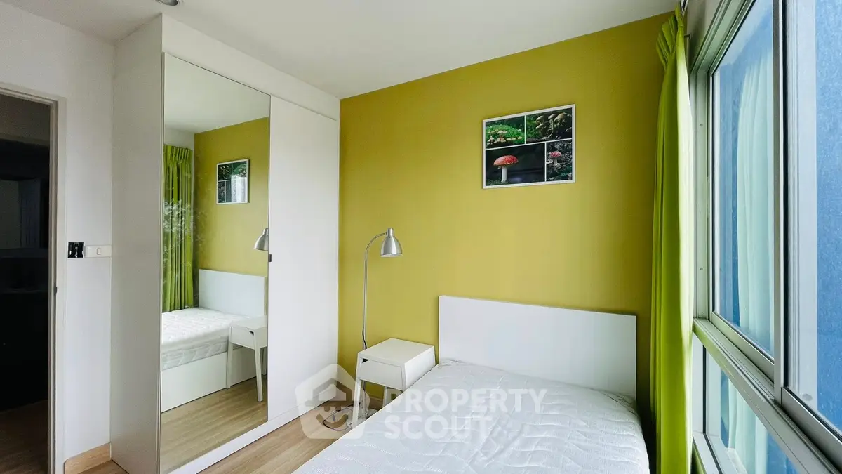 Bright bedroom with large window and mirrored closet in modern apartment