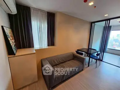 Modern living room with city view, featuring sleek furniture and large window for natural light.