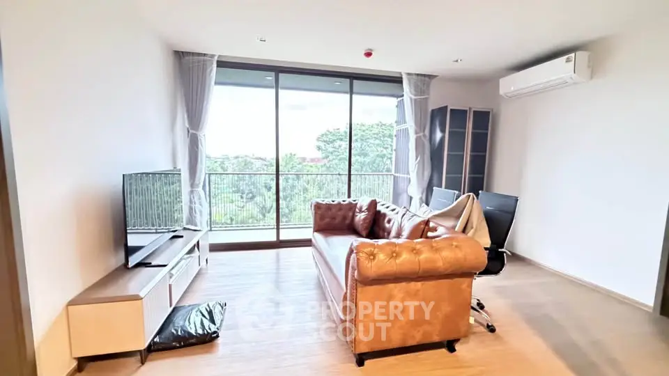 Spacious living room with leather sofa and large balcony view