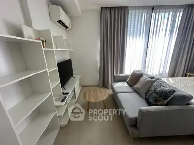 Modern living room with sleek furniture and natural light, featuring a cozy sofa and stylish shelving.