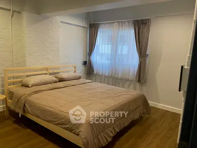 Cozy bedroom with wooden flooring and stylish brick accent wall, perfect for relaxation.