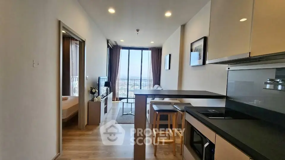 Modern open-plan apartment with kitchen and living area, featuring a stunning city view.