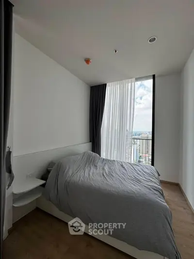 Modern bedroom with large window offering stunning city view, minimalist design and cozy atmosphere.