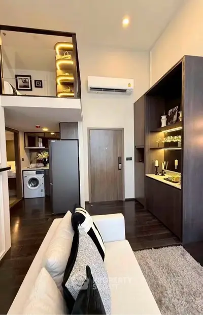 Modern loft apartment with stylish interior, featuring a cozy living area and a compact kitchen with washing machine.
