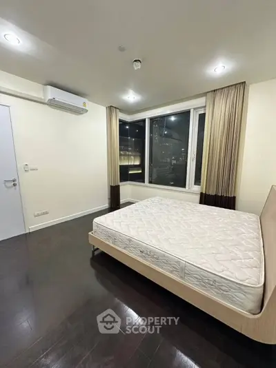 Spacious bedroom with large window and city view, featuring a comfortable bed and modern lighting.