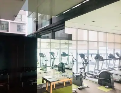 Modern gym with large windows and exercise equipment in a high-rise building.