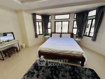 Spacious bedroom with large windows and elegant decor in modern apartment.
