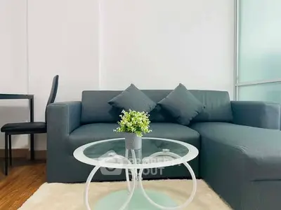 Modern living room with stylish gray sofa and glass coffee table in a bright, minimalist setting.
