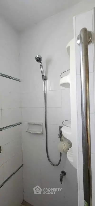 Compact bathroom shower area with white tiles and modern fixtures