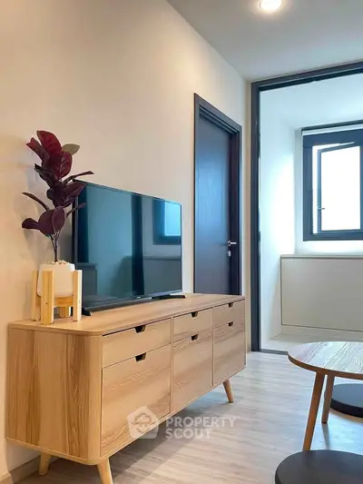 Modern living room with sleek wooden furniture and flat-screen TV, featuring minimalist design and natural light.