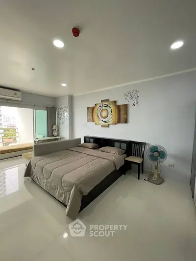 Spacious bedroom with modern decor and large window offering natural light and city view.