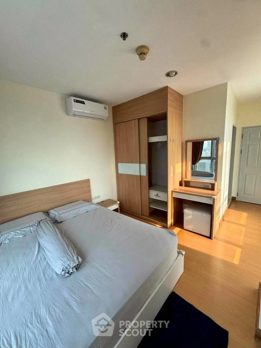 Modern bedroom with wooden furniture and natural light, featuring a cozy bed and built-in wardrobe.