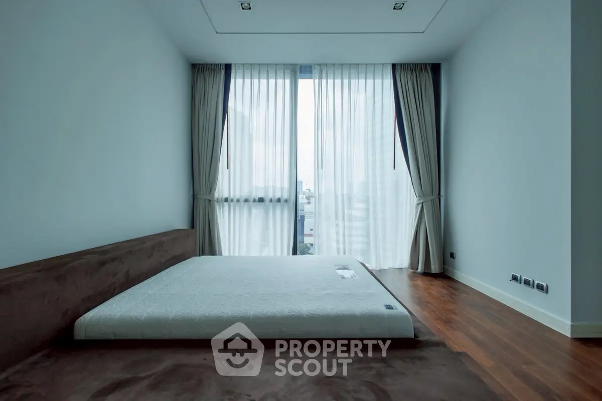 Spacious minimalist bedroom with large windows and elegant curtains