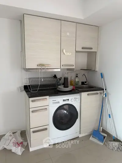 Compact kitchen with washing machine and modern cabinetry, ideal for small apartments.