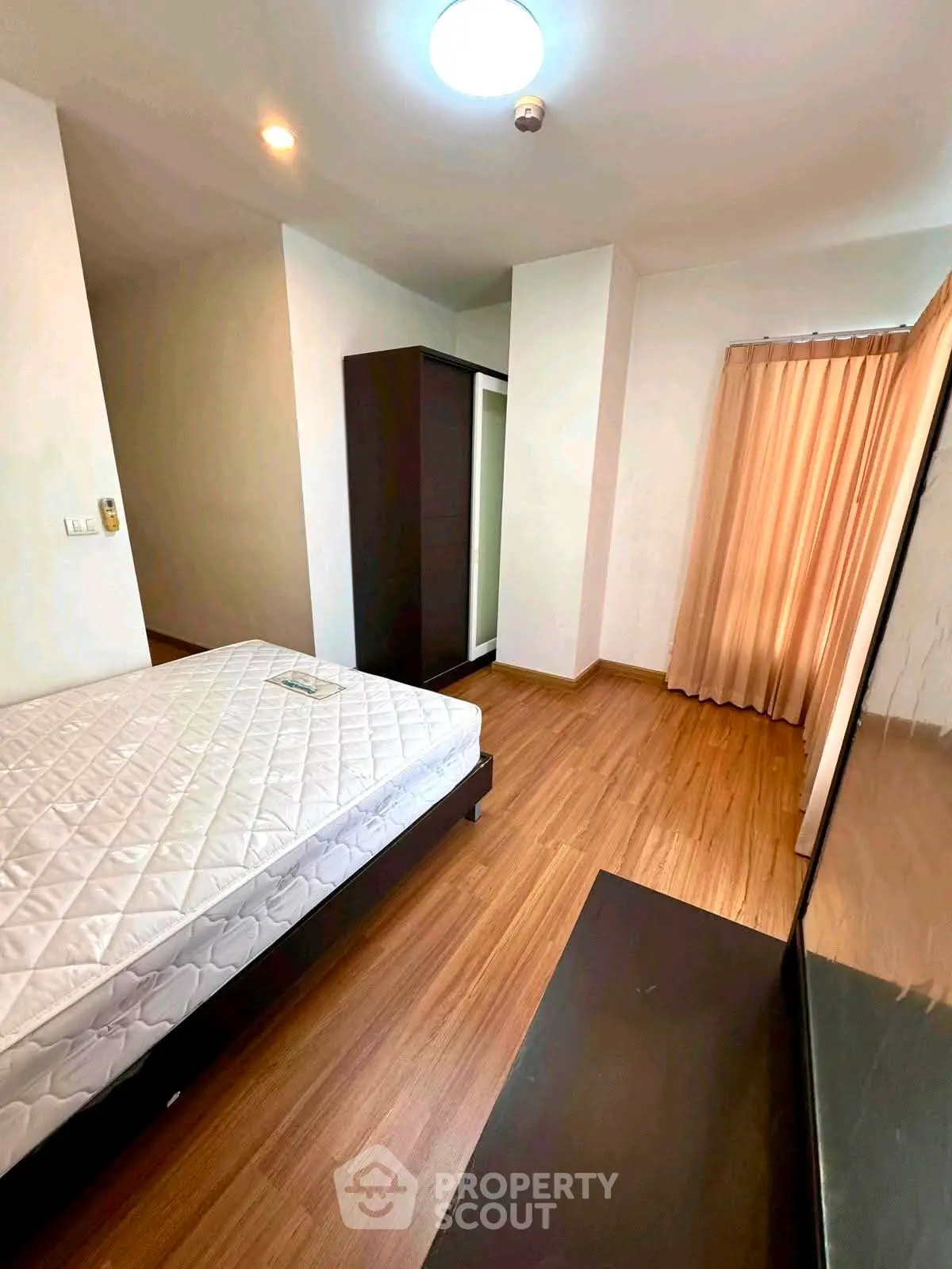 Spacious bedroom with wooden flooring and ample natural light, featuring a large wardrobe and cozy ambiance.