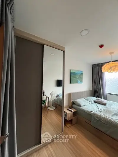 Cozy bedroom with modern decor, featuring a large mirror wardrobe and stylish lighting.