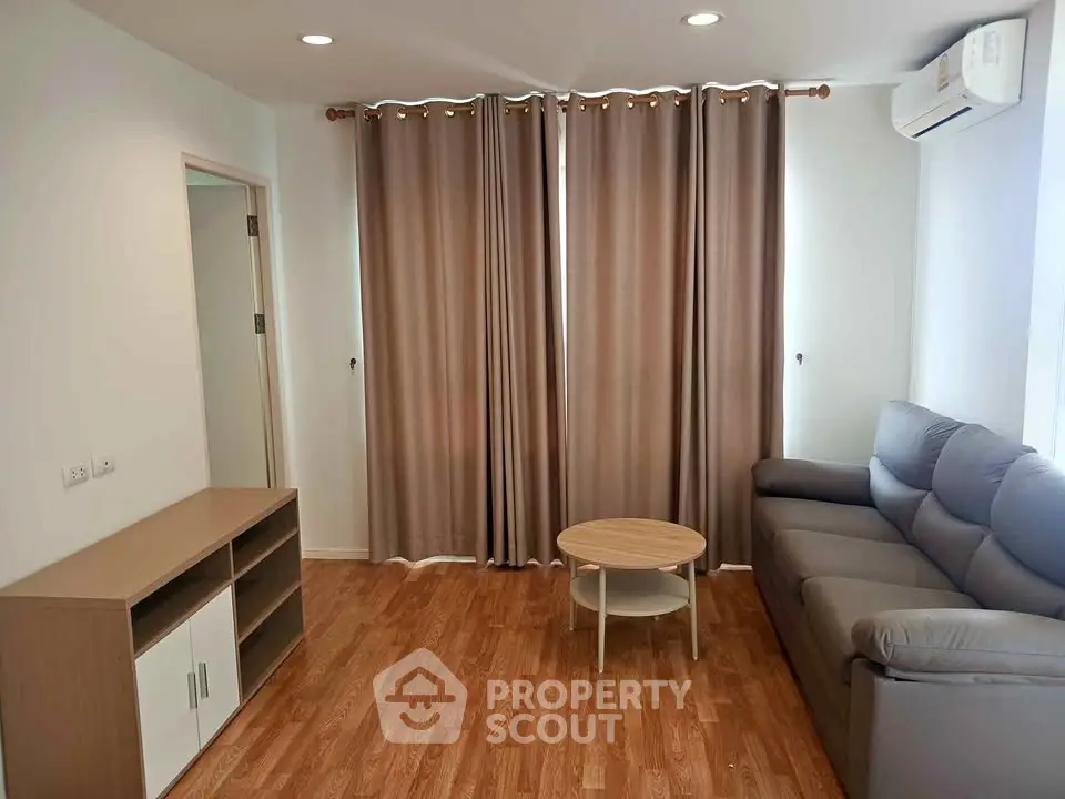 Modern living room with wooden flooring, gray sofa, and stylish curtains in a cozy apartment.