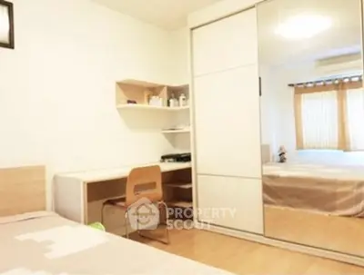 Cozy bedroom with mirrored wardrobe and study desk, perfect for modern living.
