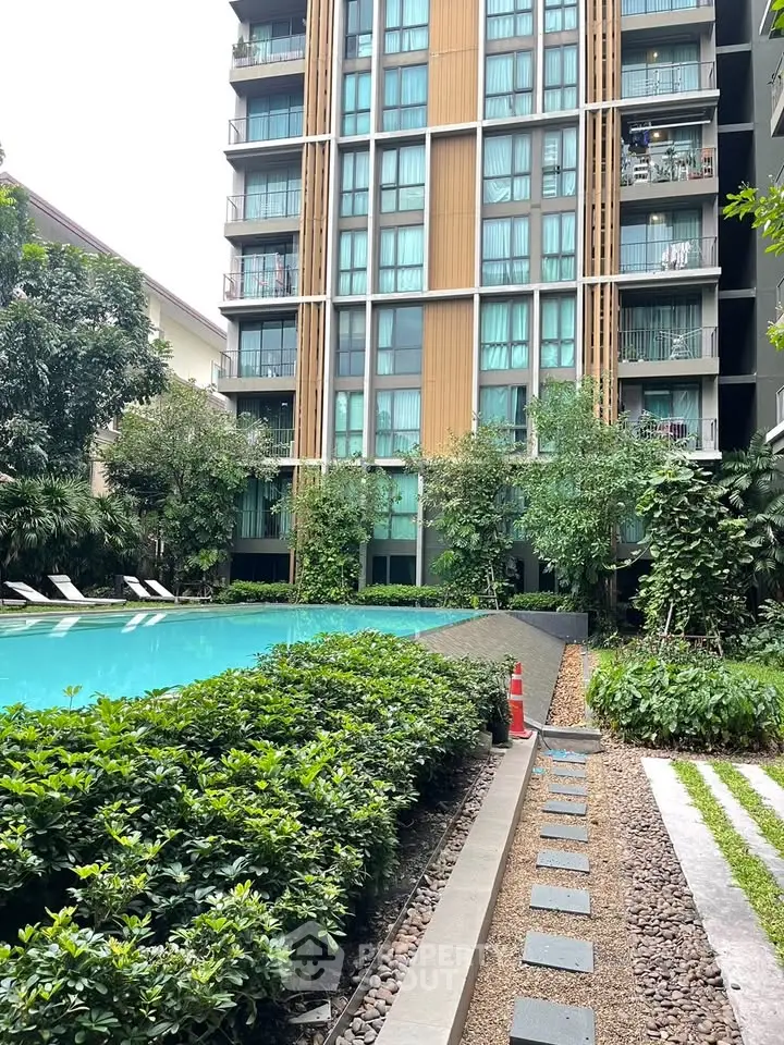 Modern residential building with lush garden and inviting swimming pool.