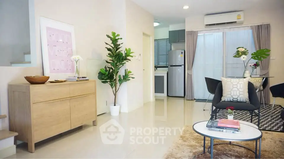 Modern living room with stylish decor and open kitchen layout, featuring sleek furniture and natural light.