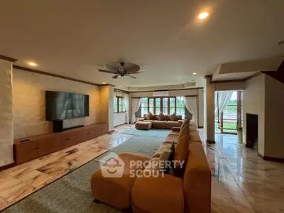 Spacious living room with modern decor and large windows offering natural light and garden view.