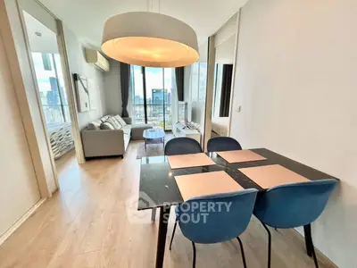 Modern open-plan living and dining area with city view, featuring stylish furniture and large windows.
